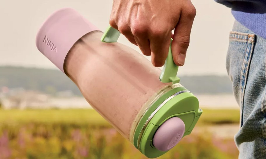 hand holding a green blender with smoothie inside 