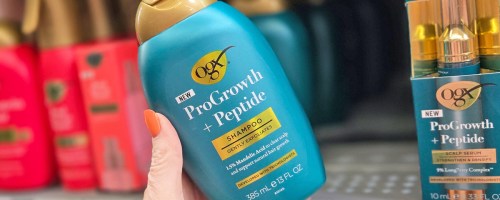 hand holding a teal bottle of OGX ProGrowth + Peptide Clarifying Shampoo in store