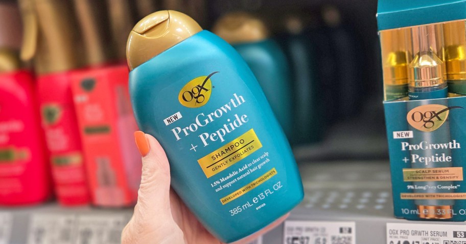 hand holding a teal bottle of OGX ProGrowth + Peptide Clarifying Shampoo in store