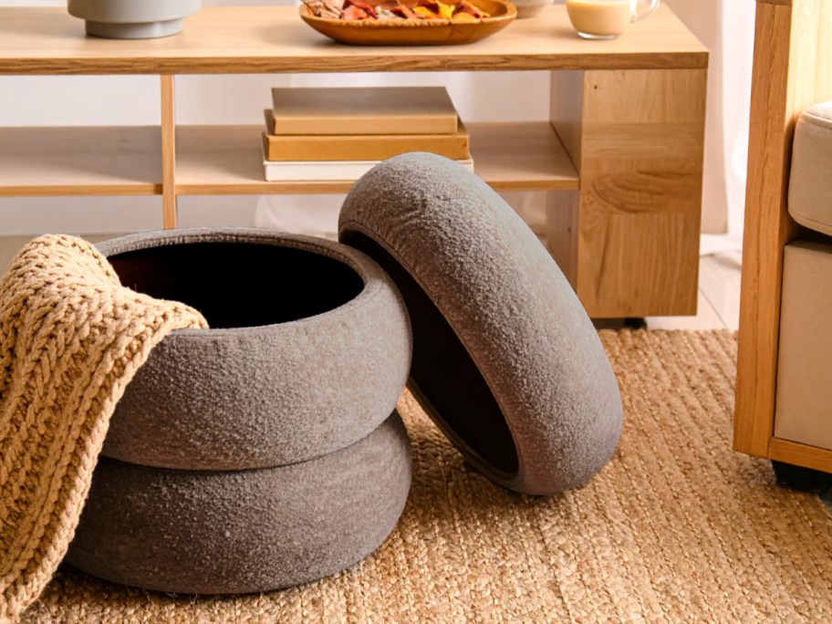 Upholstered taupe ottoman on rug in living room