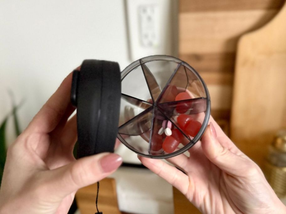 hands opening PULIV Portable Pill Dispenser Bottle in Black