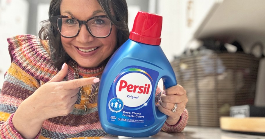 woman holding up and pointing to a bottle of persil laundry detergent