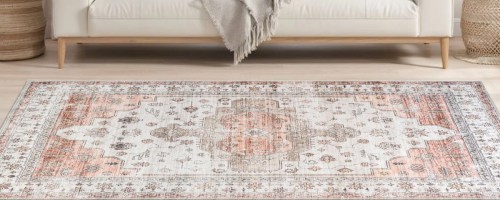 pink and white rug on floor in front of a couch