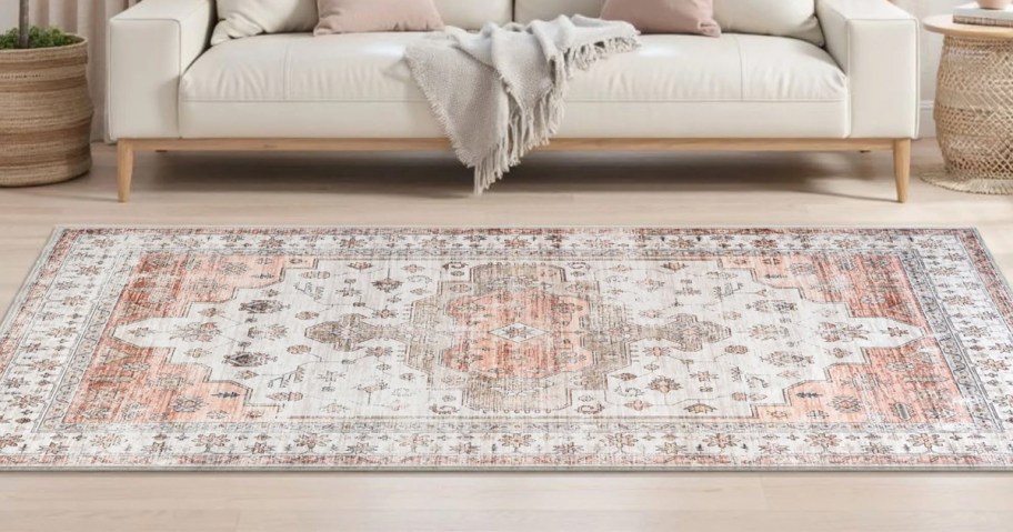 pink and white rug on floor in front of a couch