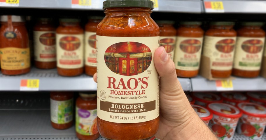 hand holding a jar of Rao's Bolognese Sauce in grocery store aisle