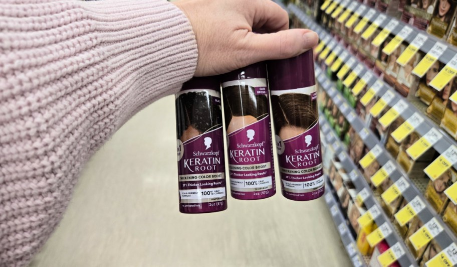 woman's arm in pink sweater holding 3 cans of Schwarzkopf keratin root spray