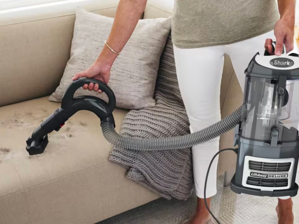 Woman, vacuuming up pet hair from couch, using shark navigator vacuum
