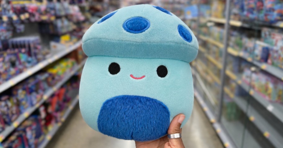 hand holding up a blue mushroom squishmallows plush in store