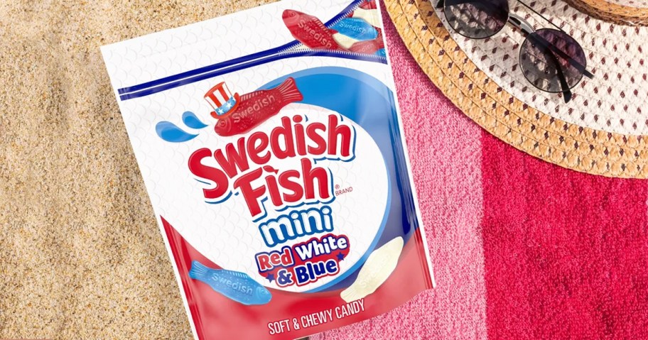 bag of red, white, & blue Swedish Fish on towel in sand