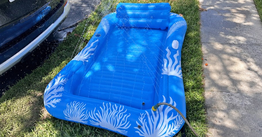 blue tanning pool with sprinklers on grass near a car