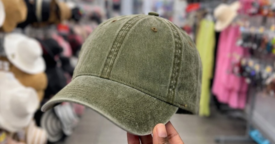 hand holding up a green baseball hat in store