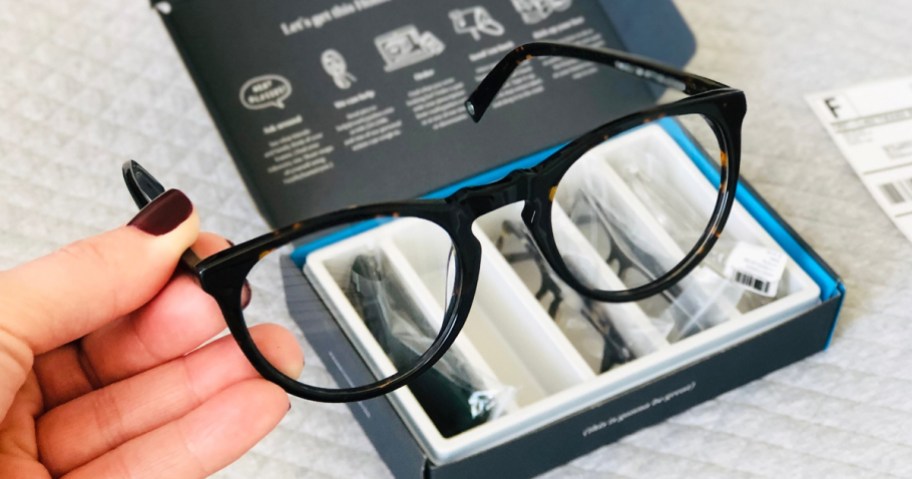 hand holding a pair of brown eyeglasses
