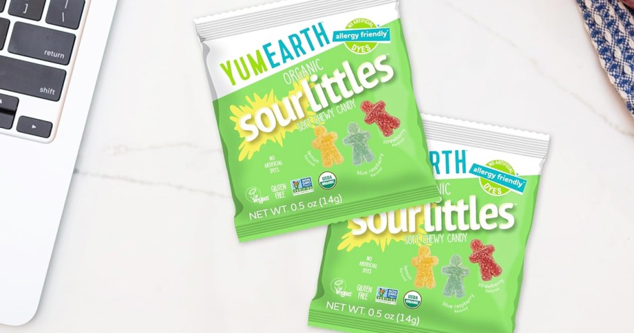 two green packs of YumEarth Organic Sour Littles candy on a desk