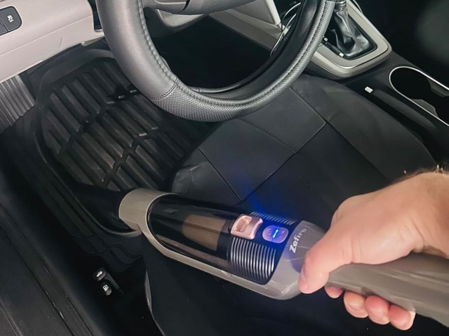 Hand using a Zephiro Handheld vacuum to clean a car out