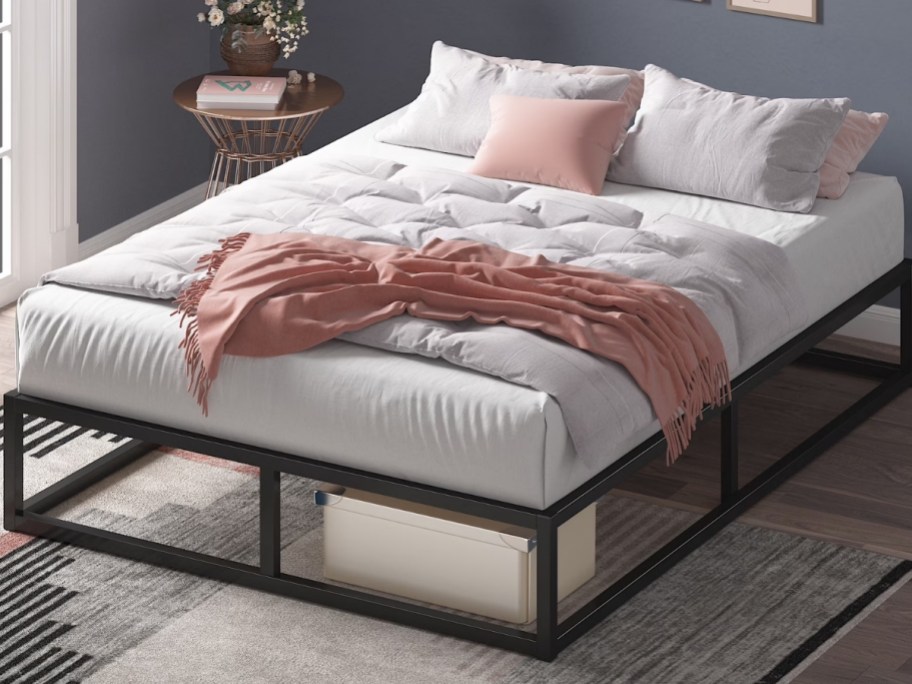 a queen platform bed with coverlet and throw pillows