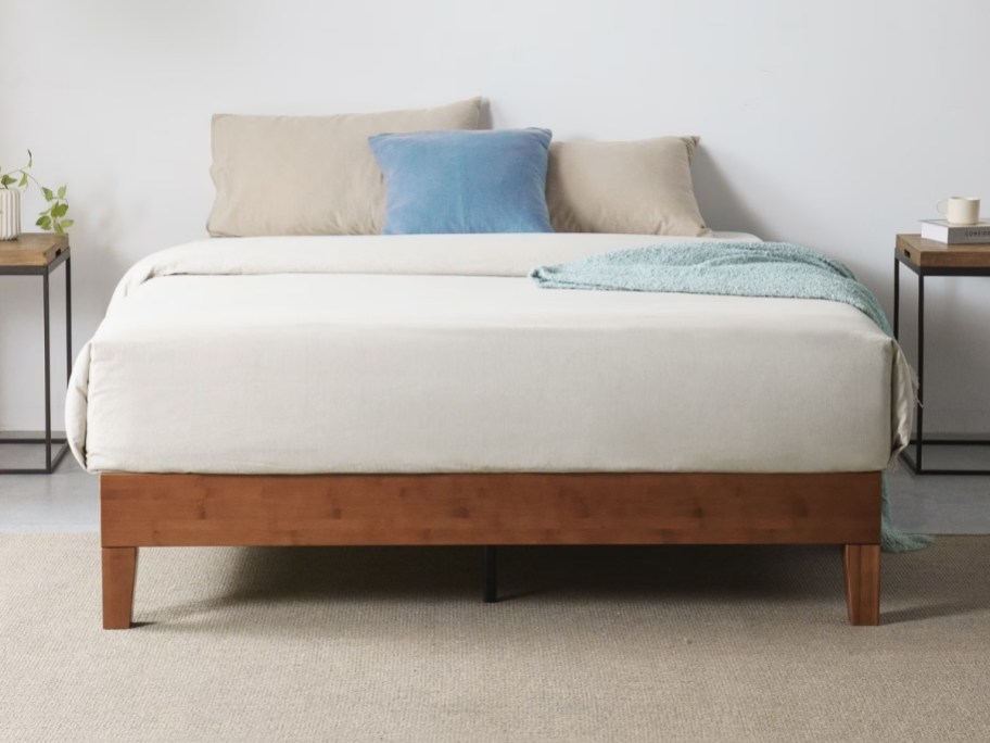 a queen bamboo platform bed with coverlet and throw pillows