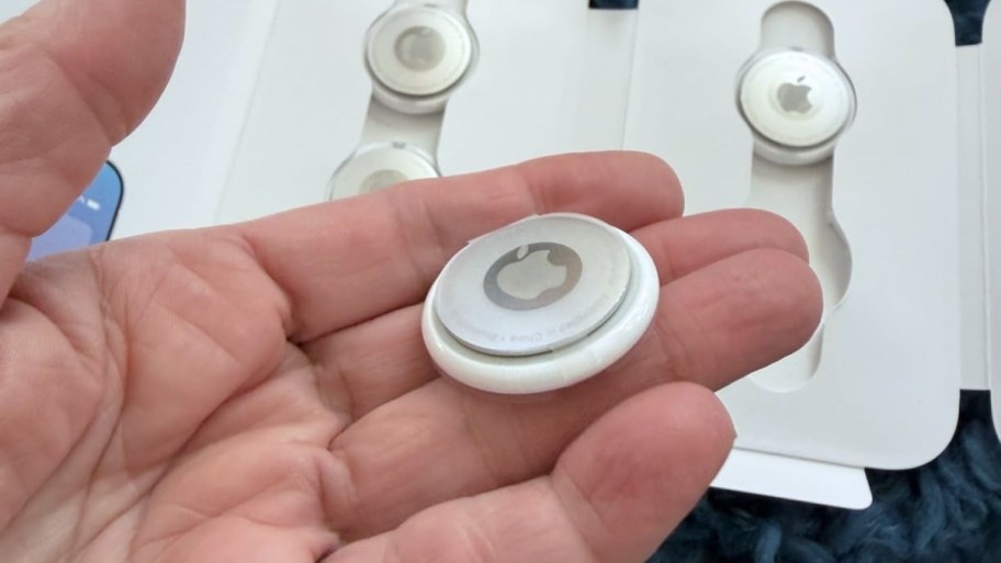 man's hand holding an apple air tag