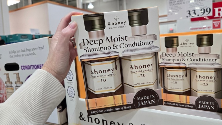 womans hand holding shampoo and conditioner set