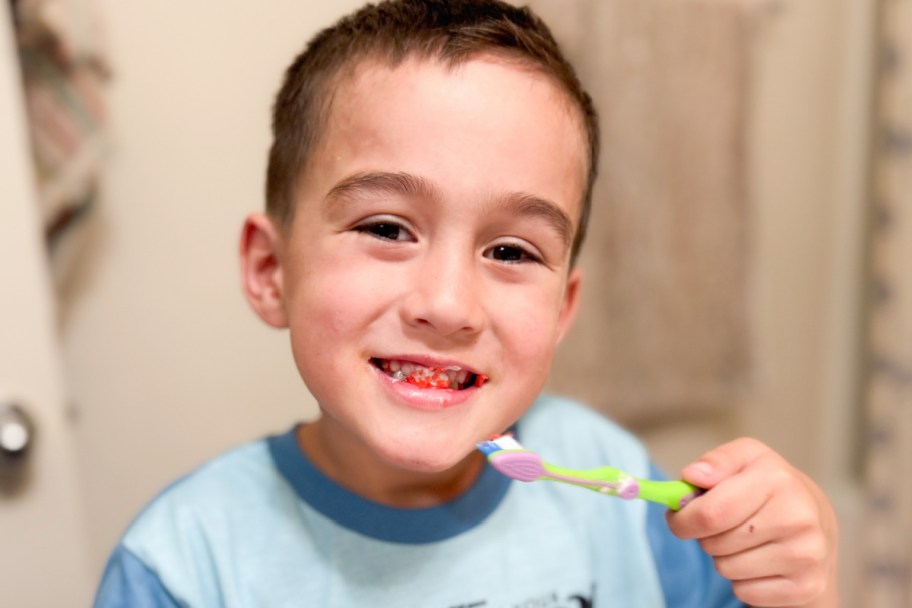 boy holding toothbrush with pop rocks toothpaste on teeth