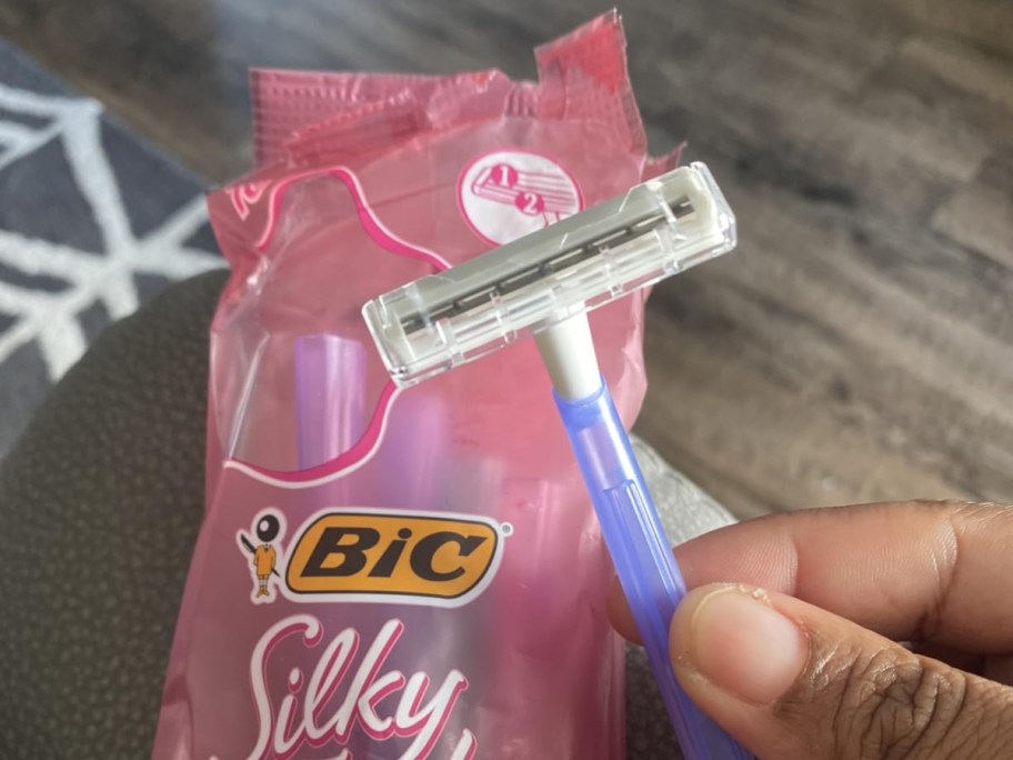 holding a purple razor in front of the packaging
