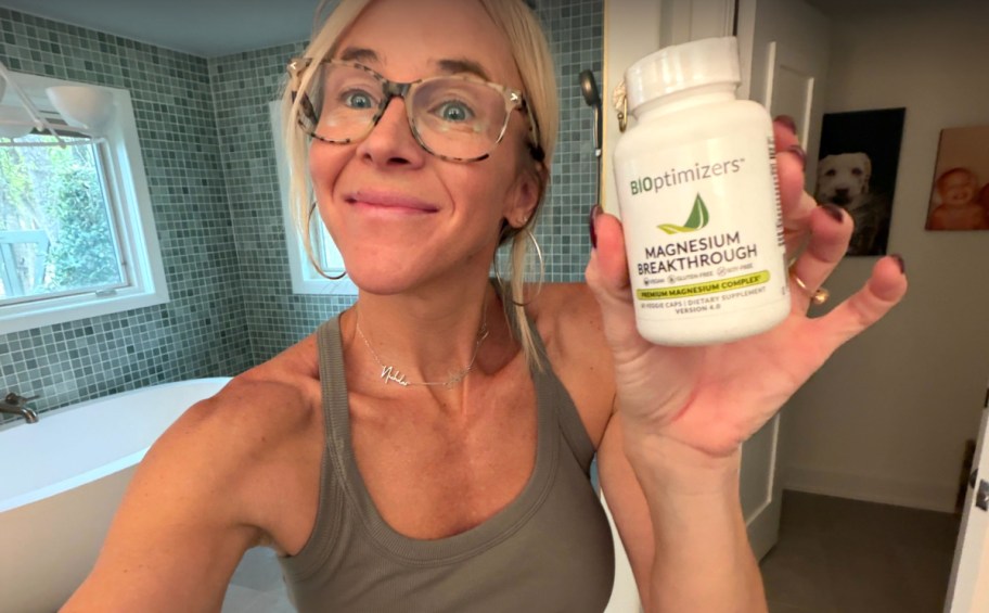 smiling woman holding a bottle of magnesium tablets