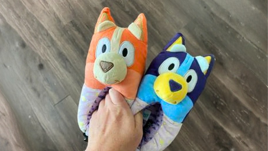 a hand holding a pair of bluey and bingo slippers