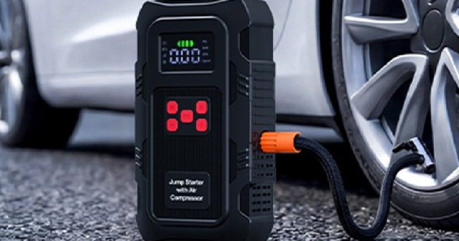 A portable car jump starter with an air compressor is connected to a car tire.