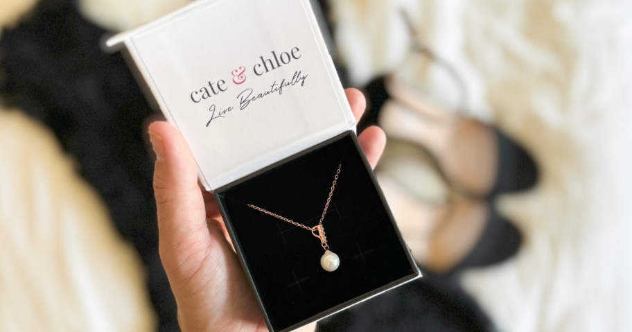 hand holding a jewelry box with a pearl necklace in it
