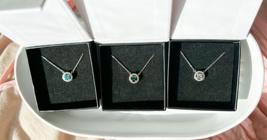 three birthstone necklaces in jewelry boxes