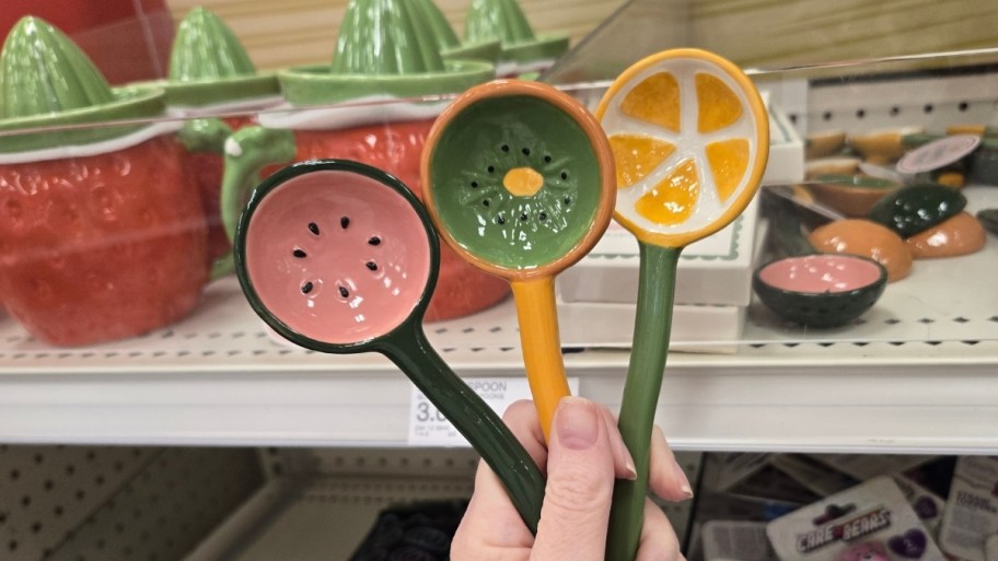 Woman's hand holding three ceramic fruit themed spoons