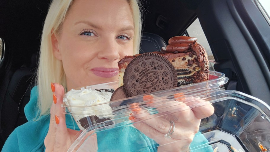 smiling woman holding a slice of oreo cheesecake
