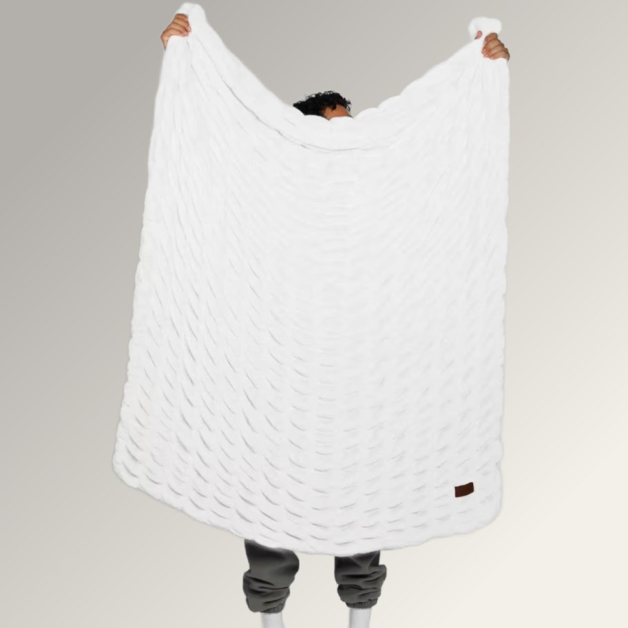 person holding up white textured blanket