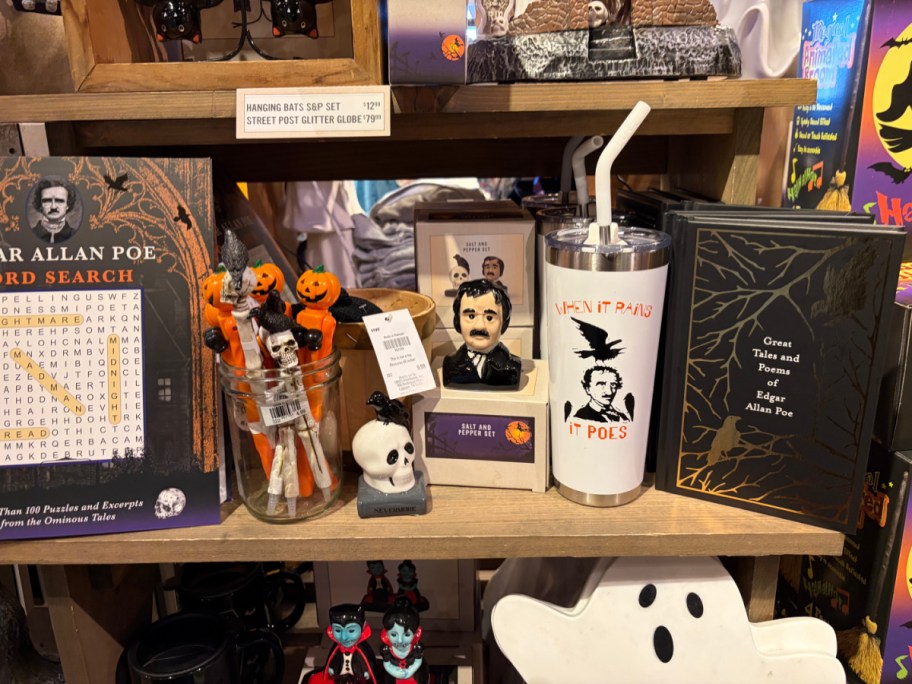 A display featuring an "Edgar Allan Poe Word Search" book with decorative items like a small pumpkin figure, cups, and other Halloween-themed merchandise.