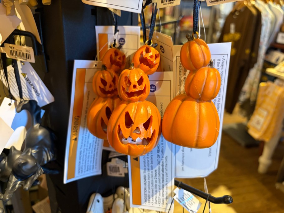 A collection of orange pumpkin ornaments with carved faces, hanging on a display.