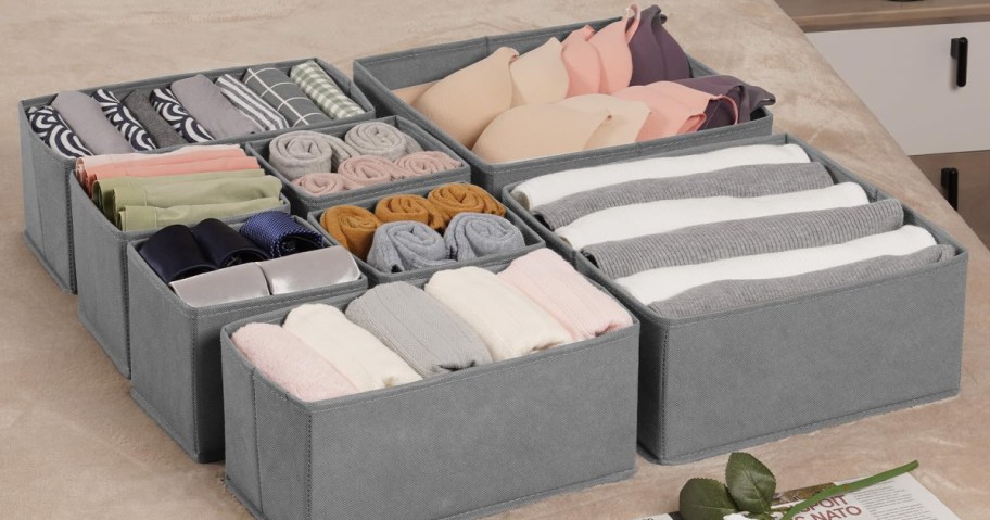 Four gray fabric storage boxes neatly contain rolled socks, folded bras, and well-organized clothing.