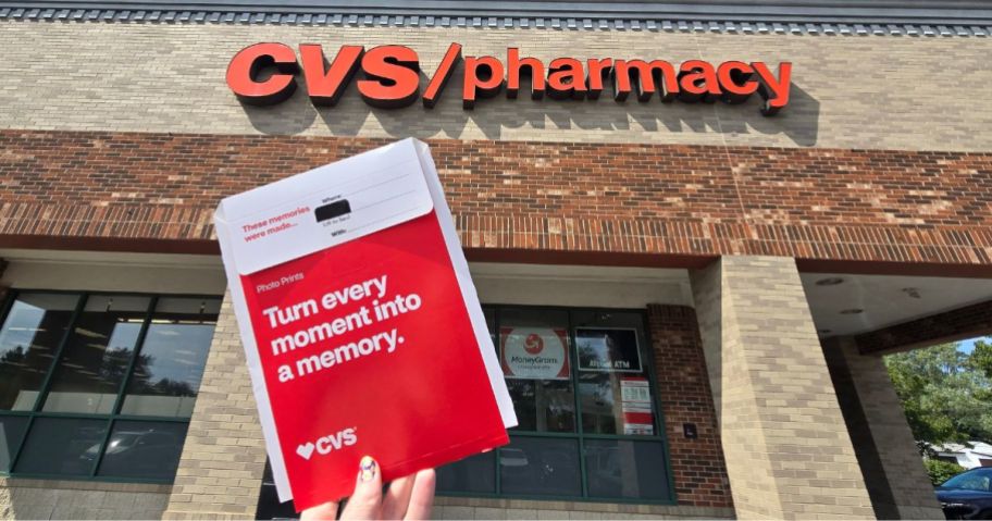 hand holding cvs photo package in front of store