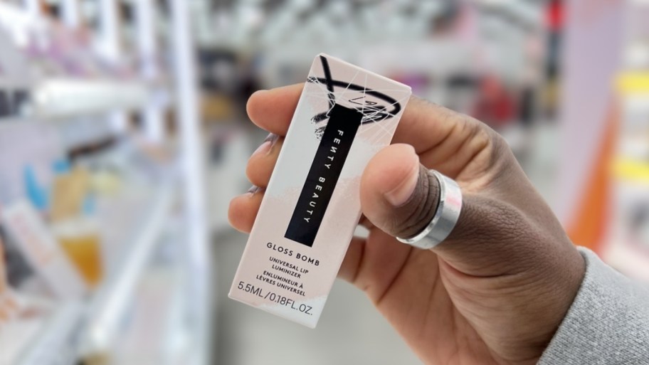 a hand holding a box with a tube of lip gloss in it