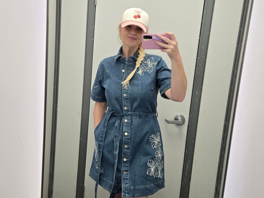 woman in denim dress and hat taking selfie