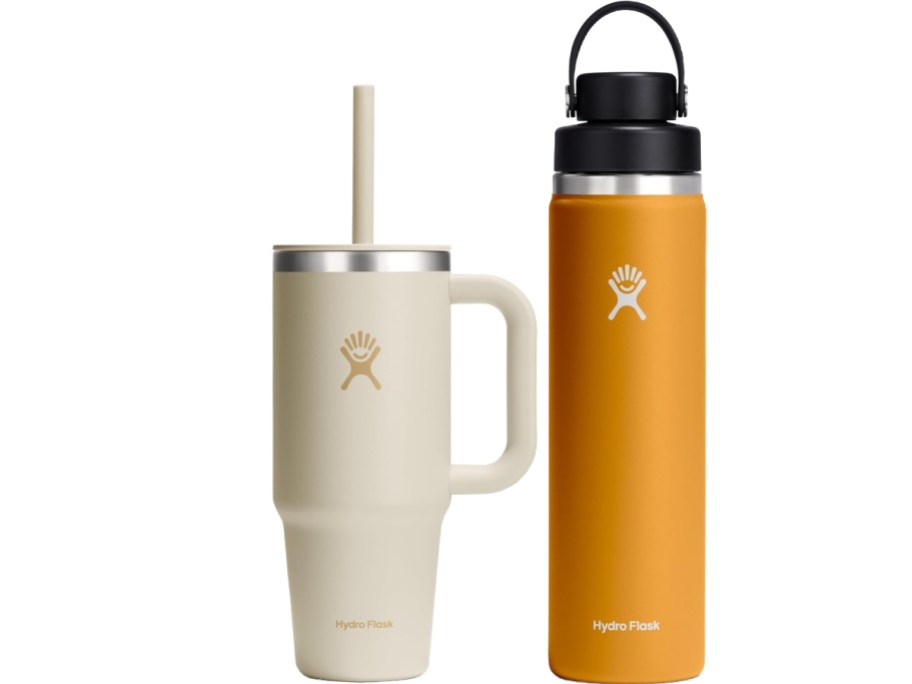 Two Hydro Flask bottles are side by side. The left is an off-white tumbler with a handle and straw; the right is a tall orange bottle with a black cap.