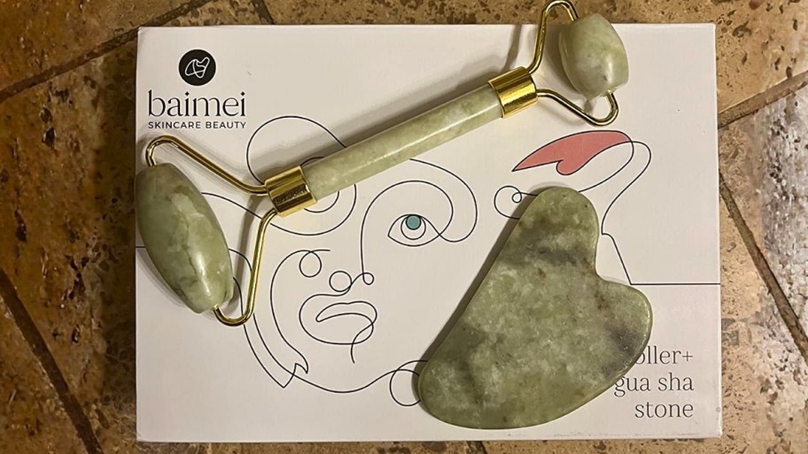 a jade facial roller and gua sha tool on top of a box