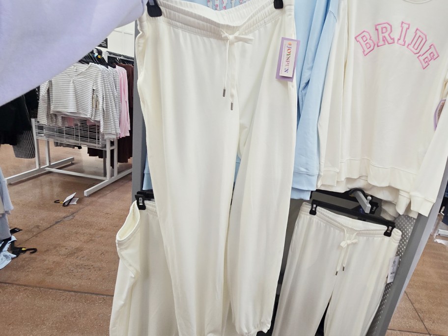 hand holding pair of white jogger pants 