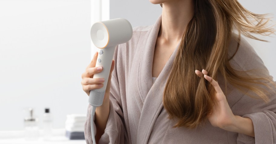 woman using a hair dryer to dry her hair