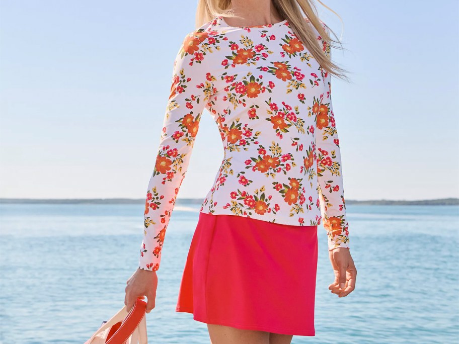 woman wearing floral rash guard and pink swim skirt 