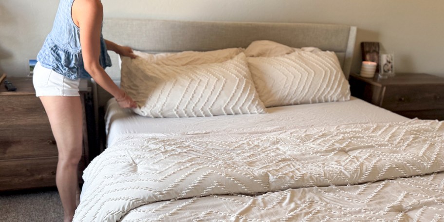 woman making bed with white bedding set