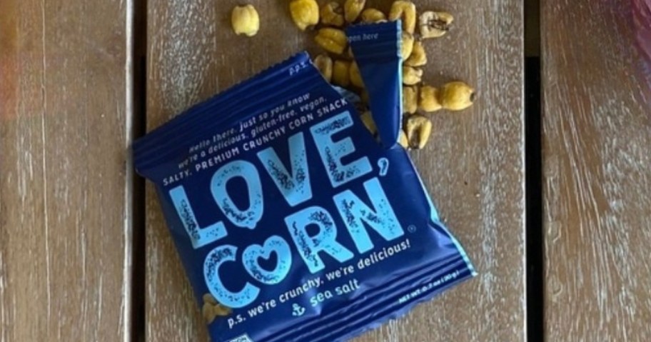 Love Corn snack bag open with corn snacks spilling out on a table