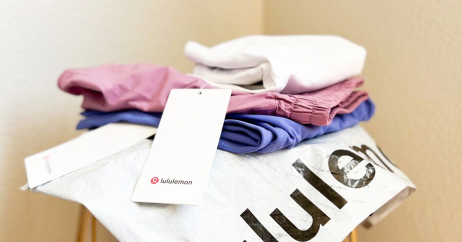 folded stack of pants and shorts on top of a lululemon shipping bag