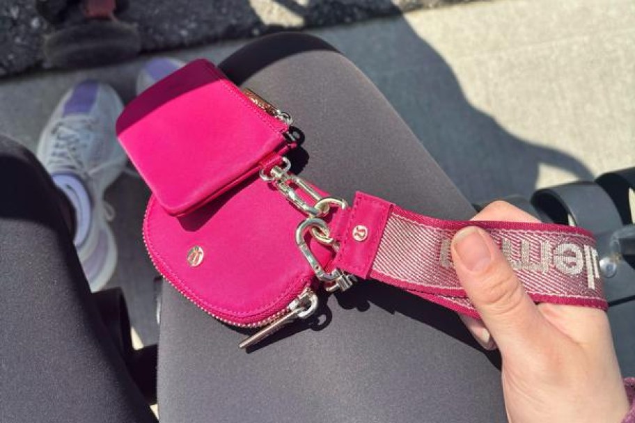 woman holding a hot pink lululemon dual pouch wristlet