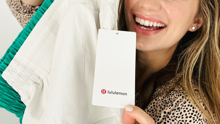 woman holding shorts and showing the lululemon brand tag