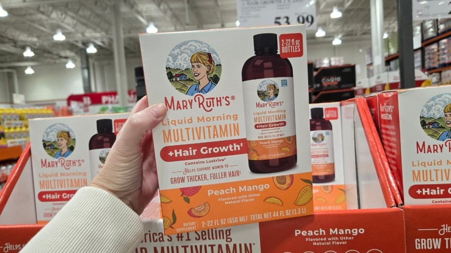 womans hand holding a bottloe of liquid vitamins