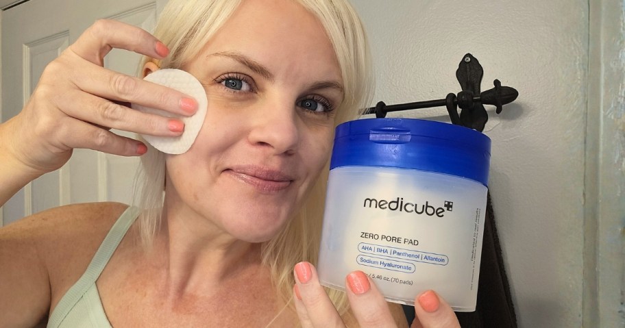 woman using a Medicube pore pad and holding a container of them